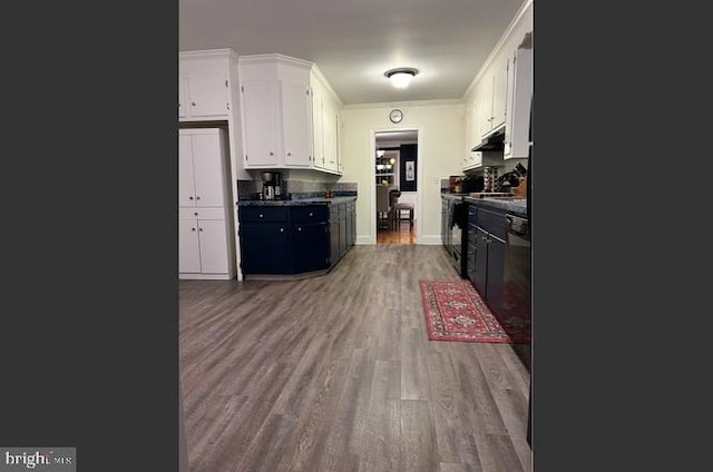 kitchen featuring white cabinetry, wood-type flooring, crown molding, and stove