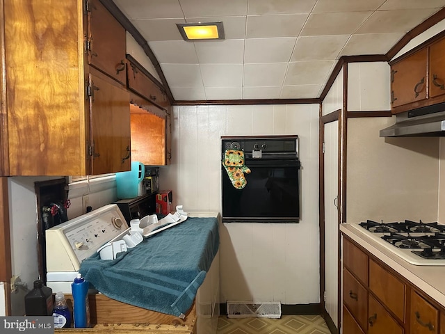 kitchen featuring oven, under cabinet range hood, white gas cooktop, light countertops, and brown cabinets