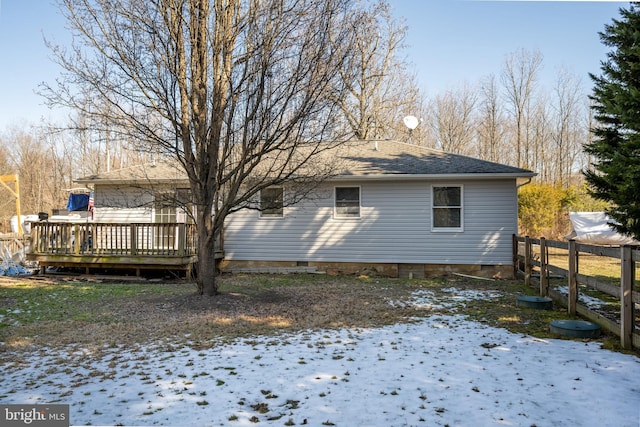 snow covered back of property with a deck