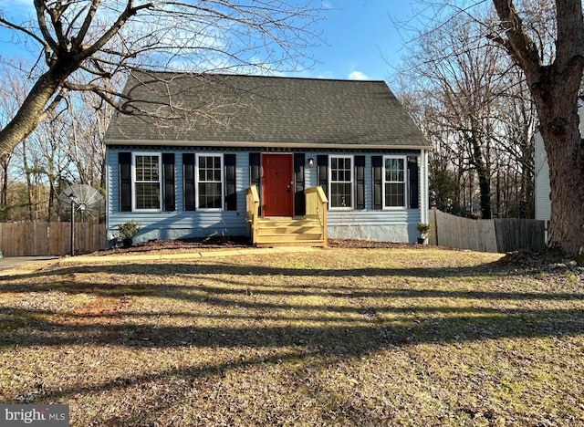 cape cod home featuring a shingled roof, fence, and a front yard