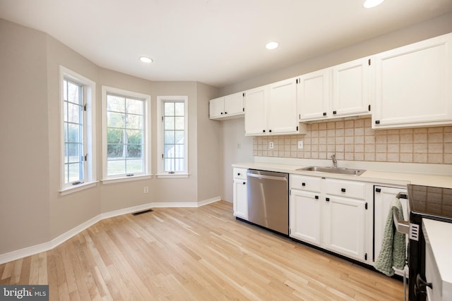 kitchen featuring tasteful backsplash, white cabinetry, sink, stainless steel dishwasher, and light hardwood / wood-style flooring