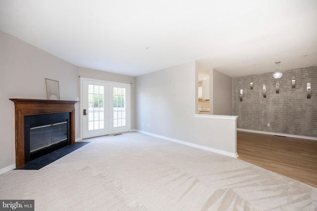 unfurnished living room featuring brick wall and light carpet