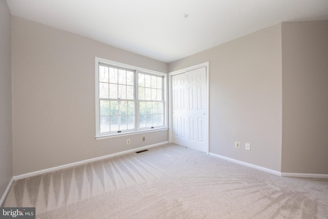 unfurnished bedroom with light carpet and a closet