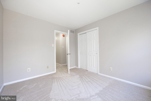 unfurnished bedroom with light carpet and a closet