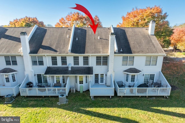 rear view of house featuring cooling unit, a deck, and a lawn