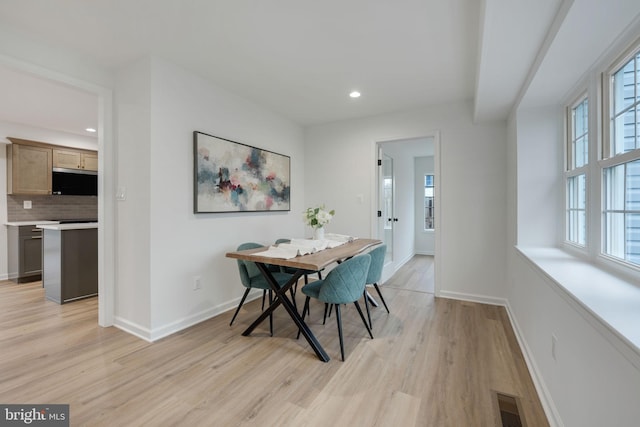 dining room featuring baseboards, light wood-type flooring, visible vents, and a healthy amount of sunlight