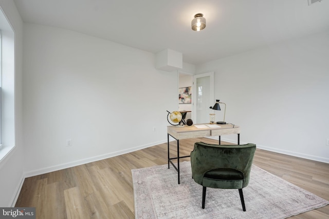 home office with light wood-style flooring, visible vents, and baseboards