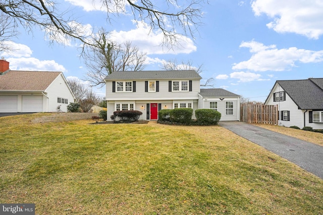 colonial house featuring fence and a front lawn