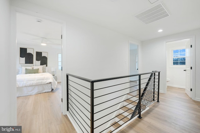 corridor featuring an upstairs landing, visible vents, light wood-style flooring, and baseboards