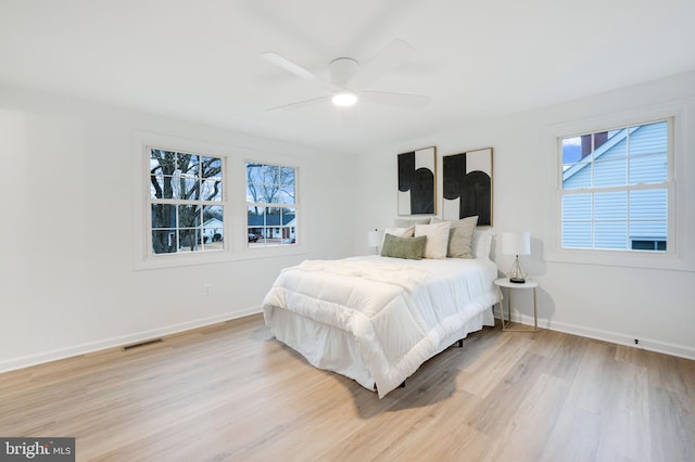 bedroom with light wood-style floors, baseboards, visible vents, and a ceiling fan