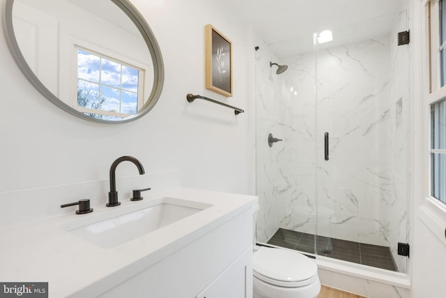 full bath featuring vanity, a marble finish shower, and toilet