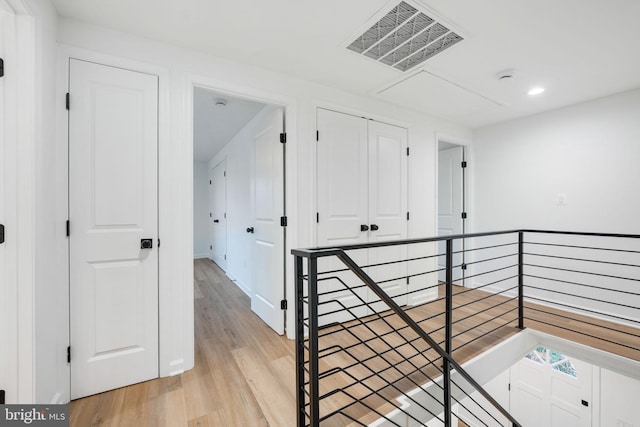 corridor with light wood finished floors, an upstairs landing, visible vents, and recessed lighting