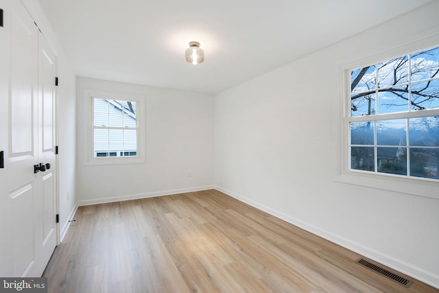 spare room featuring light wood-type flooring, visible vents, and baseboards