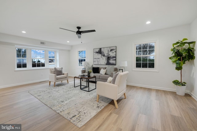 living area with a wealth of natural light, light wood-type flooring, visible vents, and recessed lighting