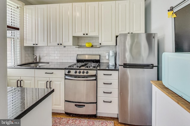 kitchen with appliances with stainless steel finishes, sink, white cabinets, and backsplash