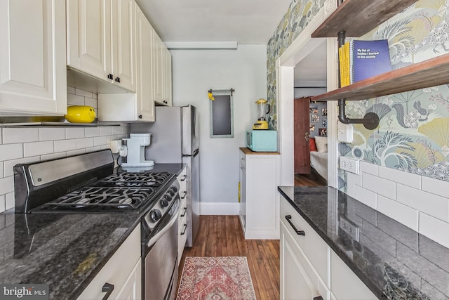 kitchen with dark wood-type flooring, gas stove, white cabinetry, tasteful backsplash, and dark stone counters