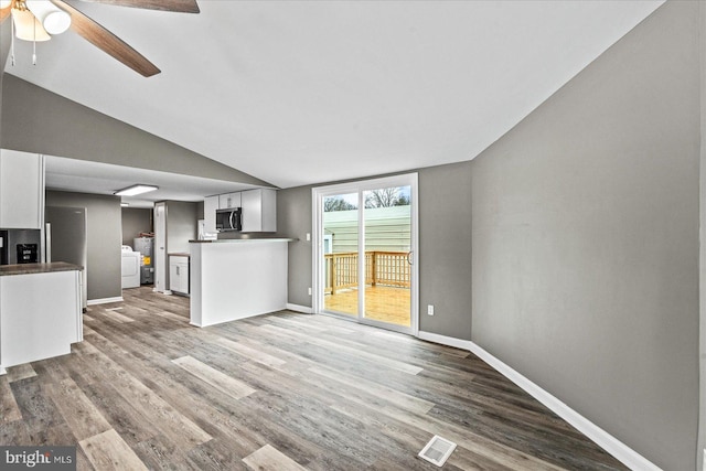 unfurnished living room featuring ceiling fan, lofted ceiling, washer / clothes dryer, and light hardwood / wood-style flooring