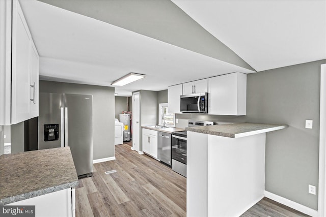 kitchen featuring white cabinetry, light hardwood / wood-style flooring, kitchen peninsula, stainless steel appliances, and washing machine and dryer