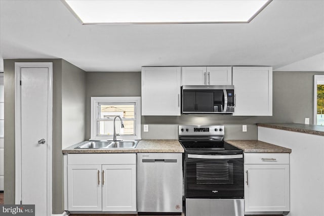 kitchen with stainless steel appliances, sink, a wealth of natural light, and white cabinets