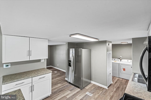 kitchen with white cabinetry, light wood-type flooring, independent washer and dryer, and stainless steel fridge with ice dispenser