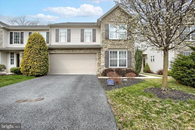 view of front of property featuring stone siding, aphalt driveway, and an attached garage