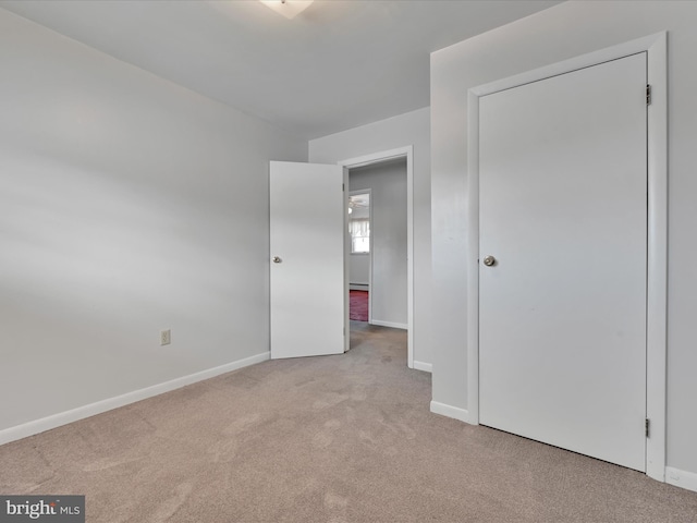 unfurnished bedroom featuring light carpet and baseboards