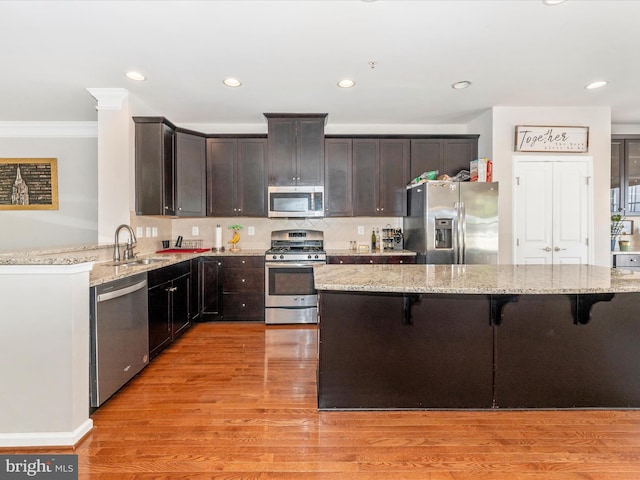 kitchen with a kitchen bar, stainless steel appliances, and light stone counters