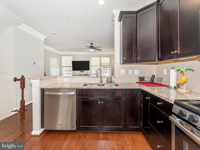 kitchen with crown molding, appliances with stainless steel finishes, sink, and light stone countertops