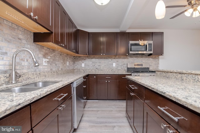 kitchen featuring dark brown cabinetry, sink, light stone counters, tasteful backsplash, and stainless steel appliances