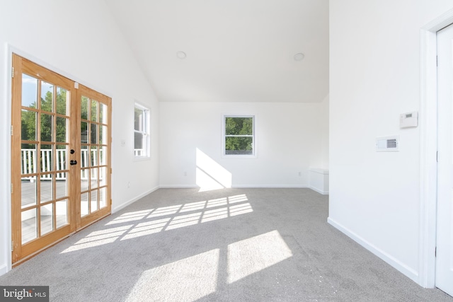 carpeted spare room with high vaulted ceiling and french doors