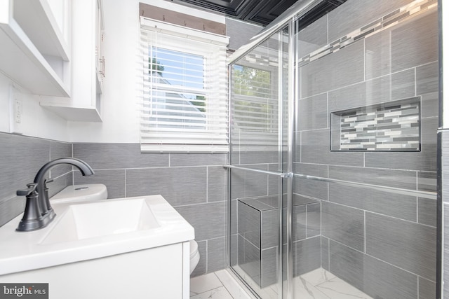 bathroom featuring vanity, toilet, a shower with door, and tile walls