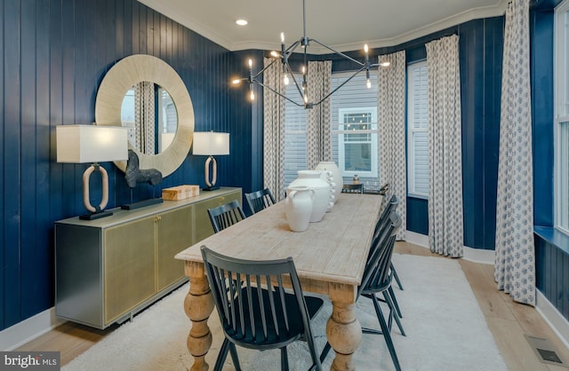 dining space featuring crown molding, an inviting chandelier, and light wood-type flooring