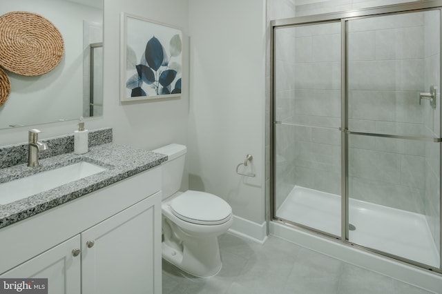 bathroom with a shower with door, vanity, tile patterned flooring, and toilet