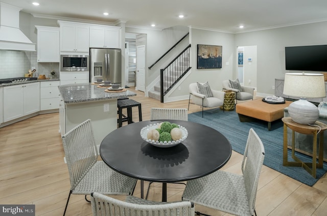 kitchen with light stone countertops, premium range hood, white cabinets, and appliances with stainless steel finishes