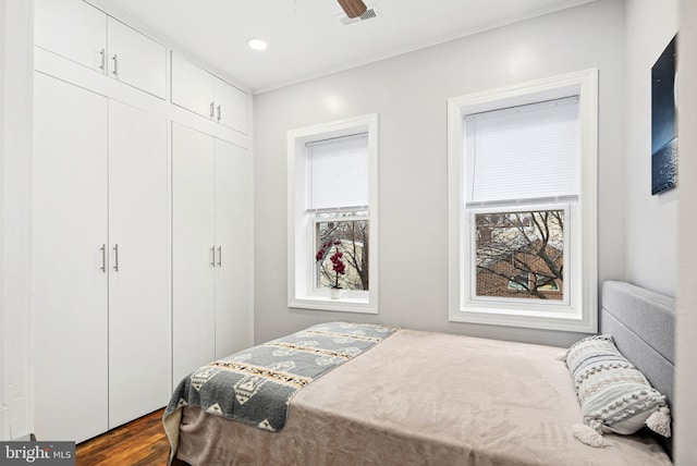 bedroom with a closet, hardwood / wood-style floors, and multiple windows