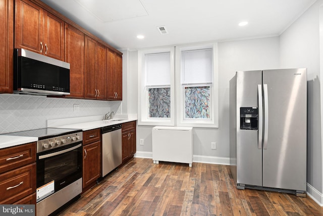 kitchen with appliances with stainless steel finishes, dark hardwood / wood-style flooring, sink, and decorative backsplash