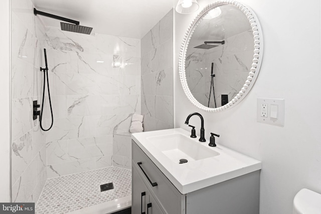 bathroom with tiled shower, vanity, and toilet