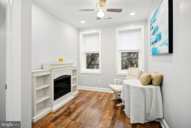 living area with crown molding, ceiling fan, and dark hardwood / wood-style flooring