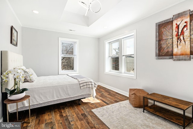 bedroom featuring wood-type flooring, ornamental molding, and a raised ceiling