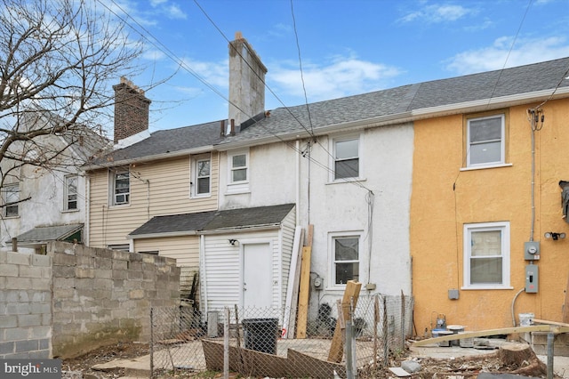 rear view of property with fence, a chimney, and stucco siding