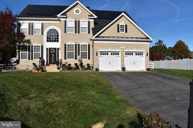 view of front of property featuring a garage, a front lawn, and solar panels