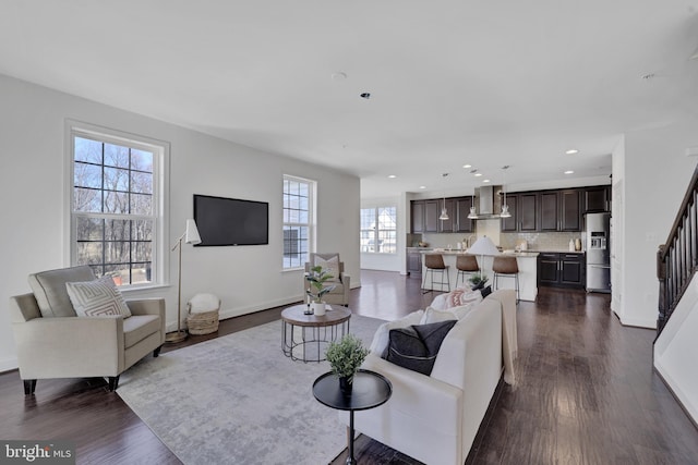 living area featuring baseboards, stairway, dark wood-type flooring, and recessed lighting