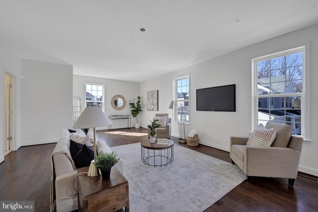 living area featuring dark wood-type flooring, plenty of natural light, and baseboards