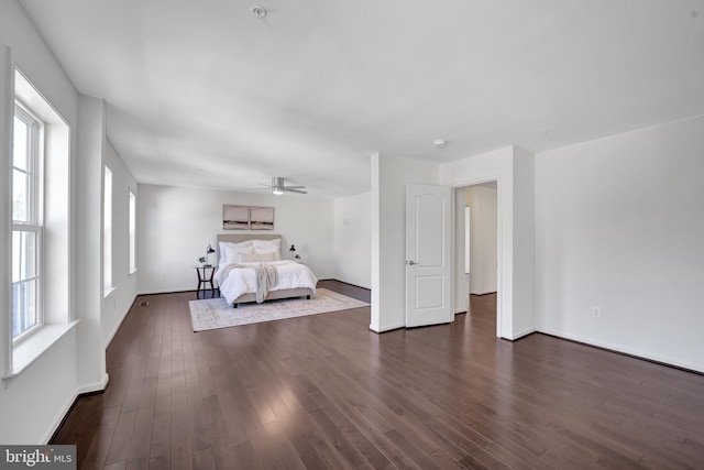 unfurnished bedroom featuring a ceiling fan, dark wood-style flooring, and baseboards