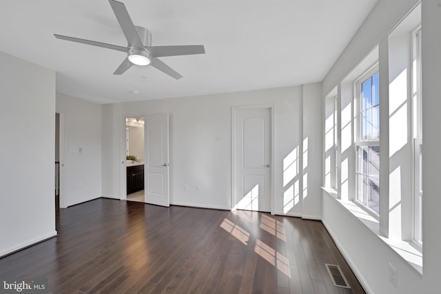 spare room with dark wood-style flooring, visible vents, ceiling fan, and baseboards