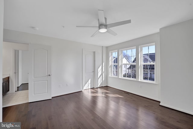 empty room with baseboards, visible vents, and wood finished floors