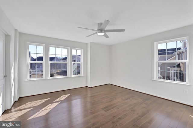 empty room with dark wood-style floors, baseboards, and a wealth of natural light