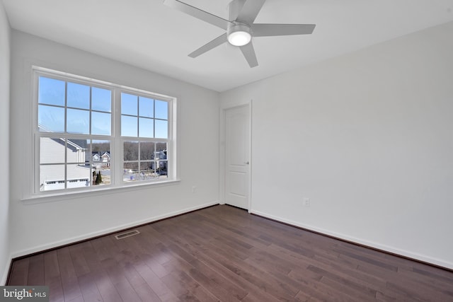 unfurnished room with dark wood-style floors, baseboards, visible vents, and ceiling fan