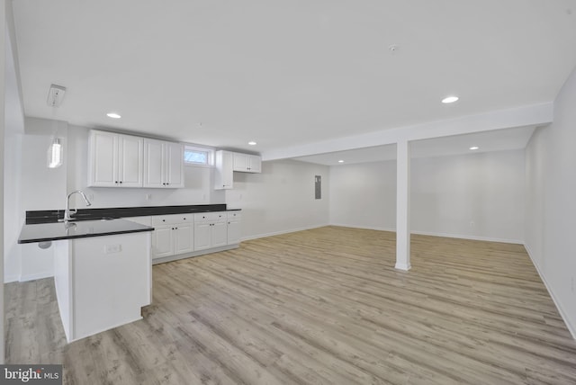 kitchen with dark countertops, open floor plan, white cabinets, and a sink