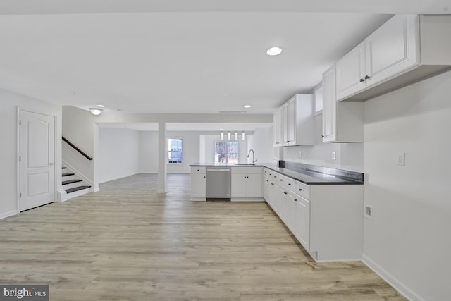 kitchen featuring dark countertops, stainless steel dishwasher, open floor plan, white cabinets, and a peninsula